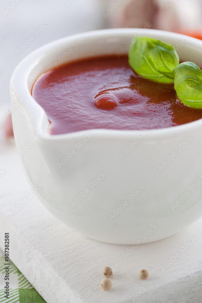 Fresh homemade tomato sauce in a white bowl on a white board, closeup, selective focus Fresh homemade tomato sauce in a white bowl on a white board, closeup, selective focus