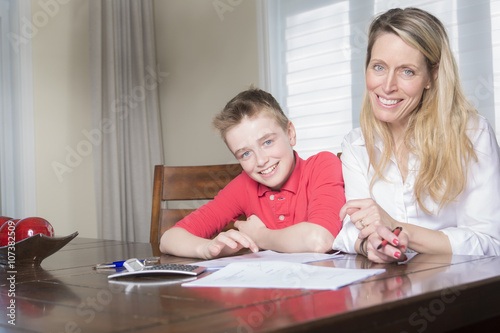 mother at a table at home helping her small son with his homework