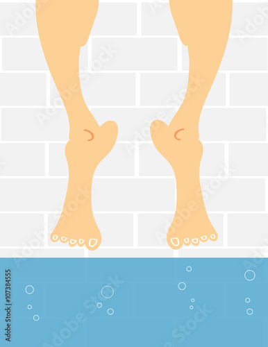 A pair of male or female feet dangling above the water in a swimming pool as if the person is afraid to take the plunge and get their feet wet