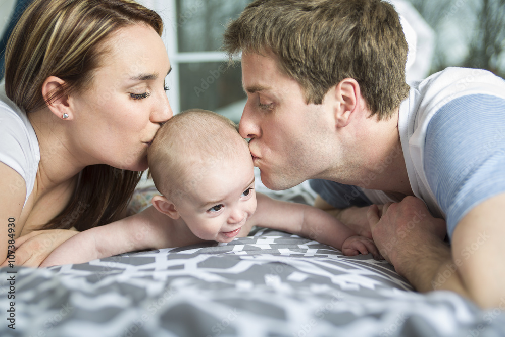 happy family of father, mother and baby playing in bed happy family of father, mother and baby playing in bed