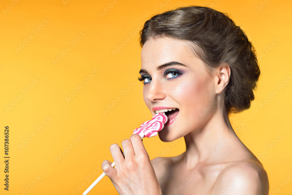beautiful young woman with pink candy over yellow backgroung beautiful young woman with pink candy over yellow backgroung