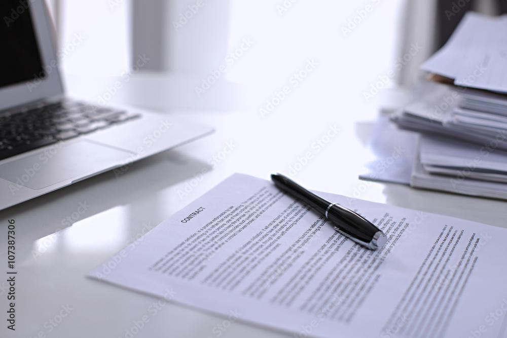.Office workplace with a laptop and contract document on the light reflecting table