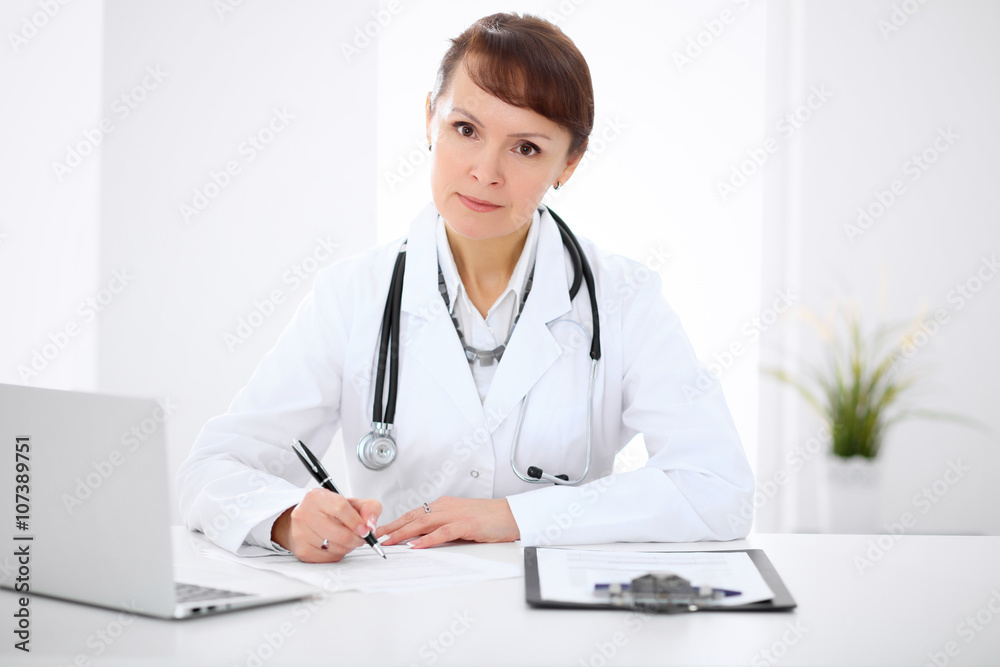 Woman doctor filling up medical history at the desk Woman doctor filling up medical history at the desk