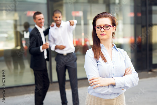 Gossip colleagues in front of their office,beautiful businesswoman portrait and gossip out of focus in background. © dusanpetkovic1