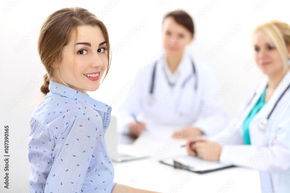 Happy smiling female patient with two cheerful doctors in the background. Medical and health care concept Happy smiling female patient with two cheerful doctors in the background. Medical and health care concept