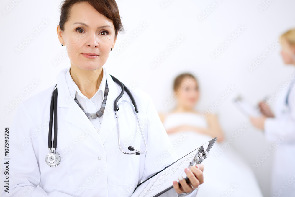 Female doctor smiling on the background with patient and his doctor Female doctor smiling on the background with patient and his doctor