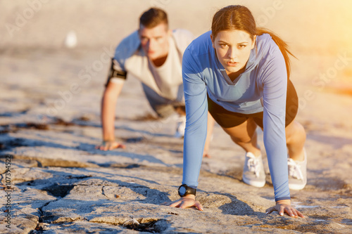 Young couple doing push ups on ocean beach