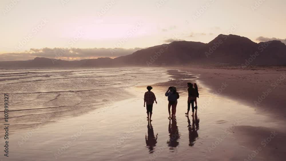 Teen friends enjoying a walk at beach on sunset