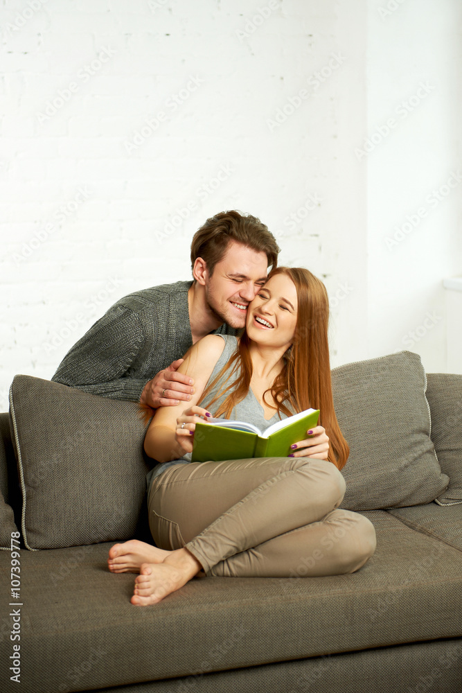 Obraz premium Young Couple Reading a Book On Sofa