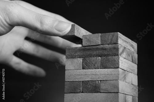 Risk and strategy, planning, Close up hand gambling placing wooden block on a tower. black and white color.