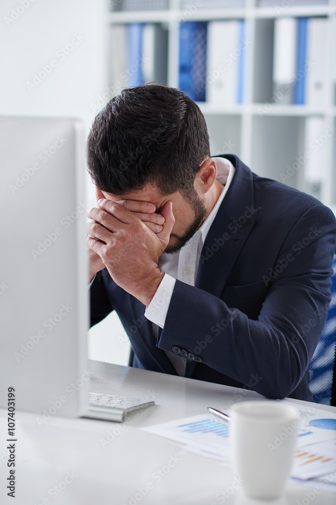 Unhappy depressed young businessman at his workplace Unhappy depressed young businessman at his workplace