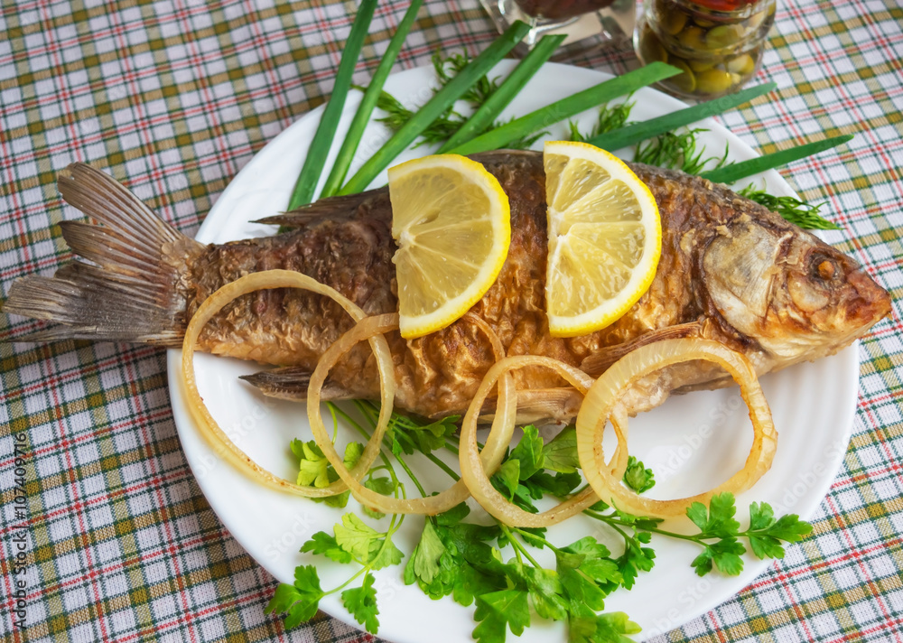 Roasted carp fish with greens on a white plate. Roasted carp fish with greens on a white plate.