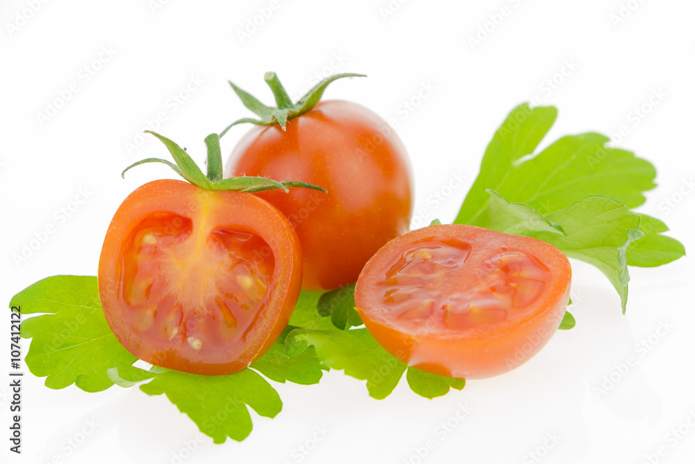 Cherry tomatoes, one cut in half, on parsley leaves. On white background. Cherry tomatoes, one cut in half, on parsley leaves. On white background.