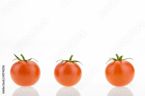 Three cherry tomatoes with reflections, on white background with copy-space