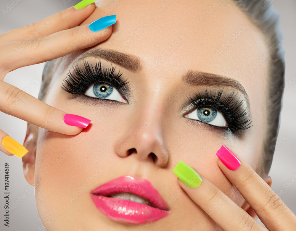 Beauty girl face with colorful nail polish. Manicure and makeup