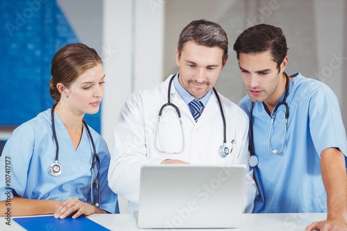 Concentrated doctors using laptop while standing at desk 