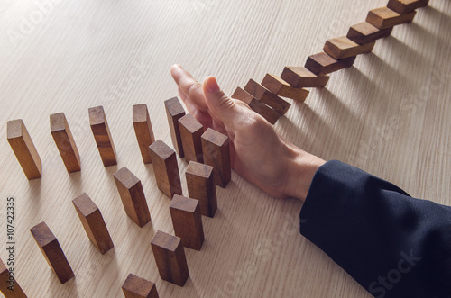 Businesswoman hand stopping the domino wooden effect concept for business. photo