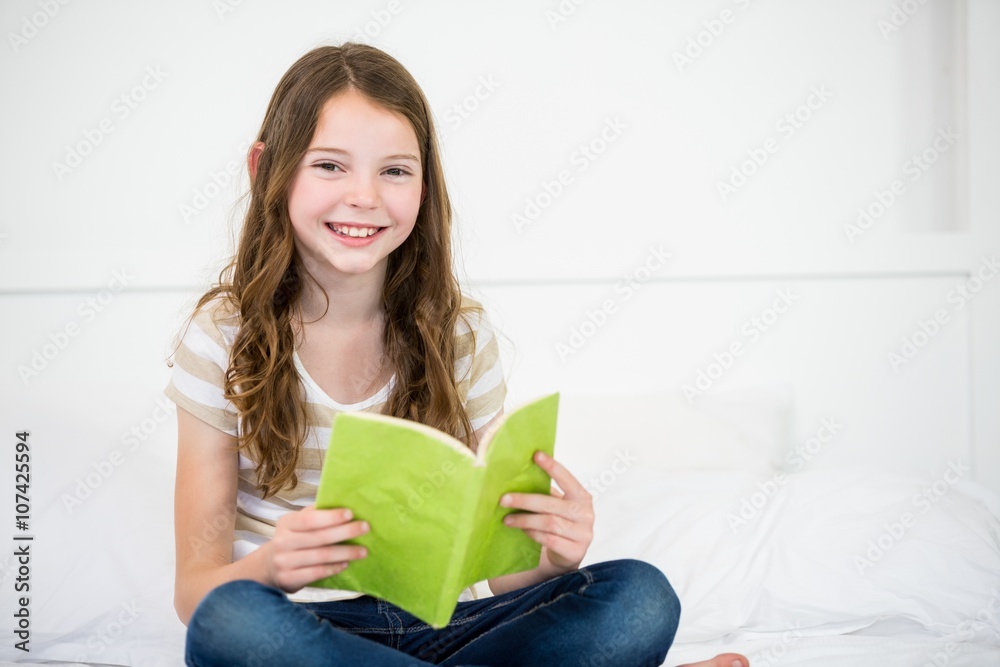 Portrait of cute happy girl reading book on bed at home Portrait of cute happy girl reading book on bed at home