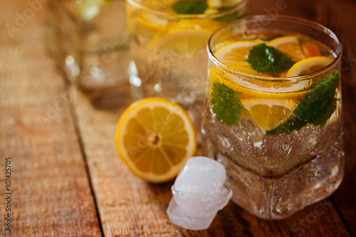 Fresh lemon drink with sugar and mint on wooden background