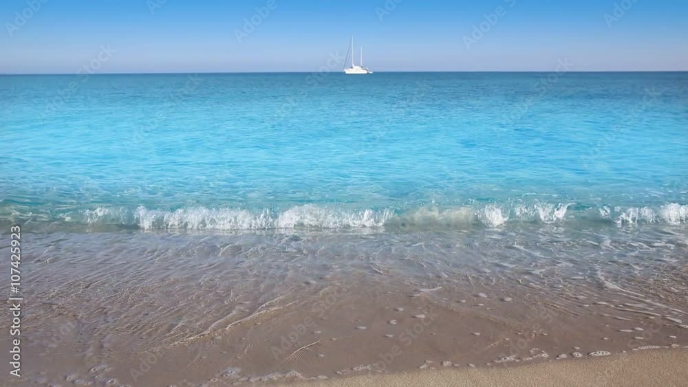 Perfect beach with sailboat in turquoise aqua color and the waves in the shore sand Perfect beach with sailboat in turquoise aqua color and the waves in the shore sand