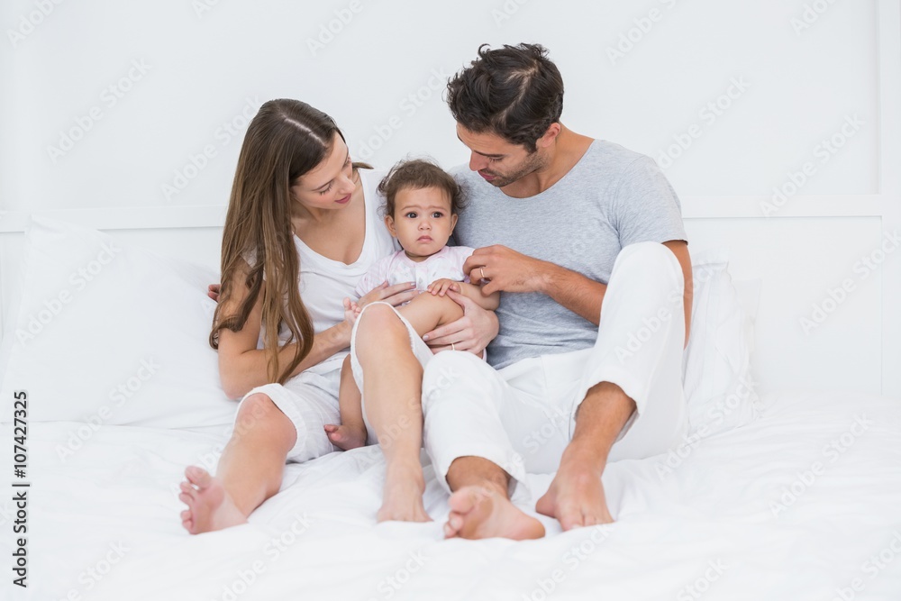 Parents with child sitting on bed 