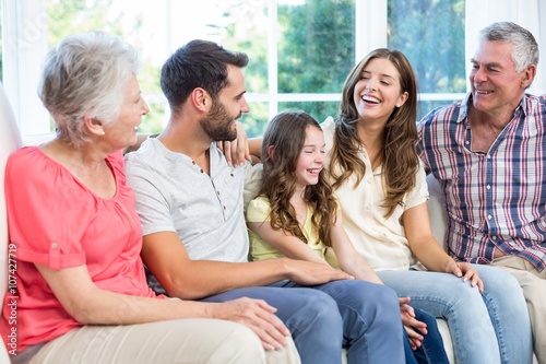 Multi-generation family smiling while sitting on sofa 