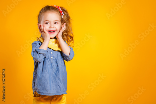 Funny little girl on a bright yellow background.