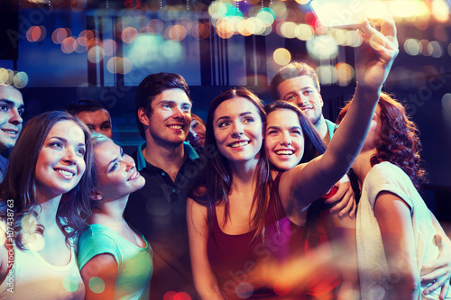 friends with smartphone taking selfie in club