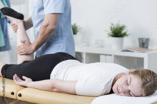 Masseur massaging female customer's leg