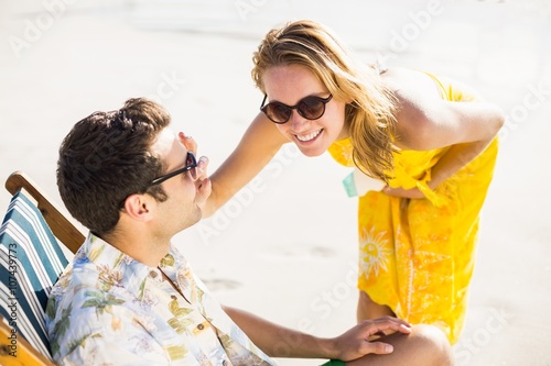 Happy woman applying moisturizer on mans nose
