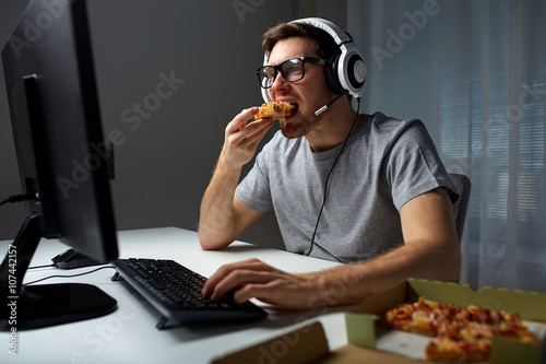 man in headset playing computer video game at home