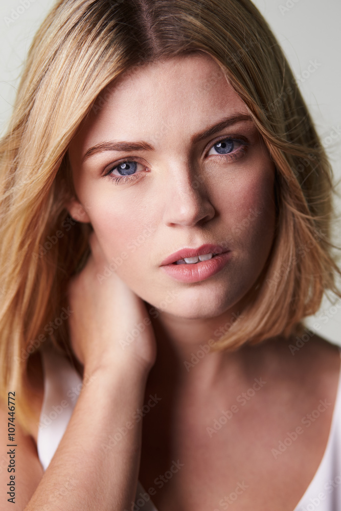 Blonde woman looking to camera, hand on neck, vertical Blonde woman looking to camera, hand on neck, vertical