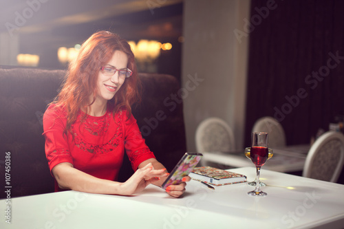 Beautiful girl talking on the phone in a cafe and drink wine