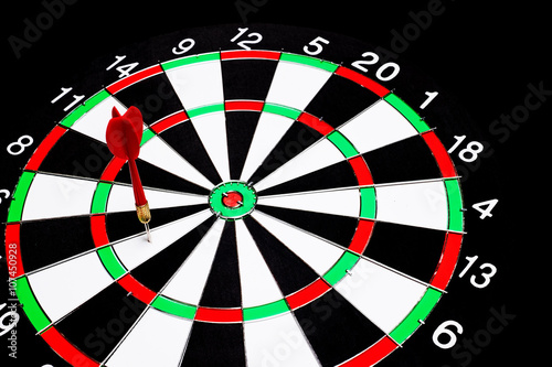 Red dart arrow failed to hit in the target center of dartboard with black background