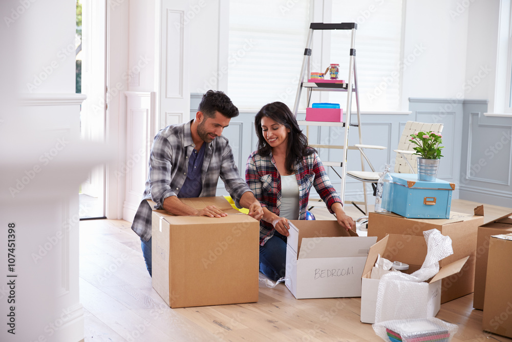 Hispanic Couple Moving Into New Home And Unpacking Boxes