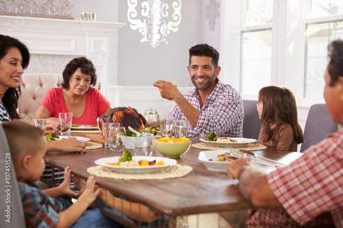 Extended Hispanic Family Enjoying Meal At Table