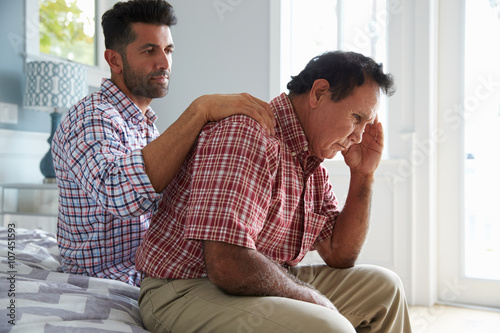 Фотография Adult Son Comforting Father Suffering With Dementia