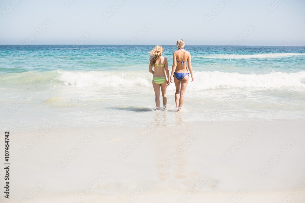 Two rear women walking on the beach
