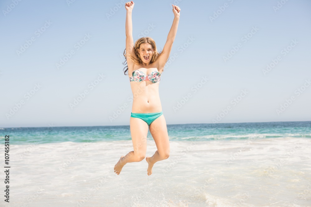 Carefree woman in bikini jumping on the beach Carefree woman in bikini jumping on the beach