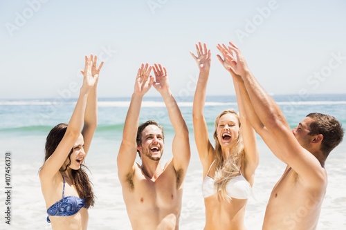 Happy friends raising their hands on the beach