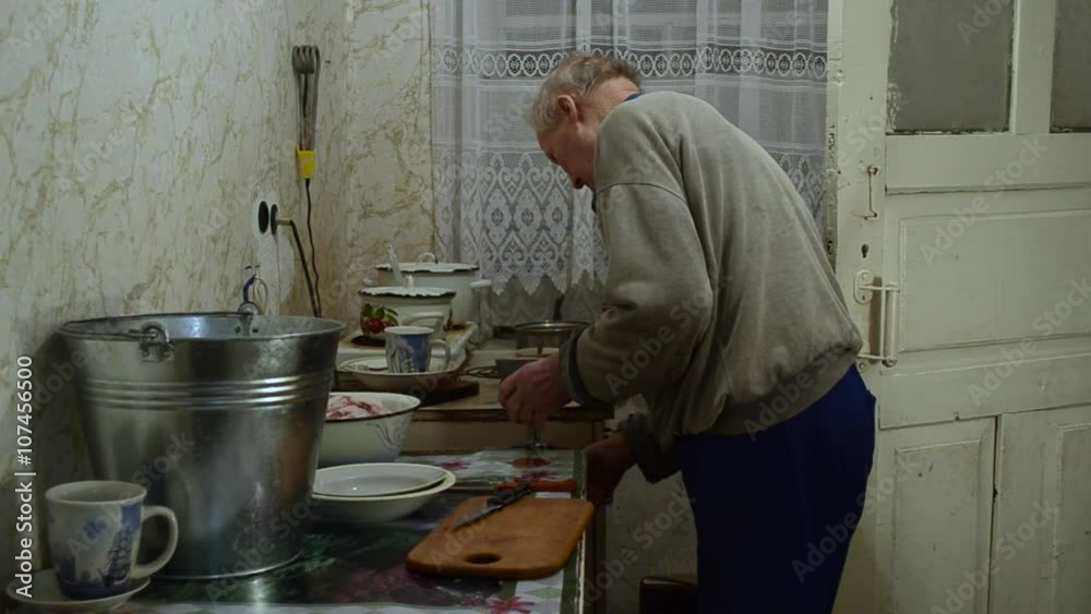 Elderly Man Installs a Meat Grinder on Table Edge Elderly Man Installs a Meat Grinder on Table Edge
