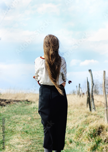 Beautiful fairytale young woman in traditional clothes walking &