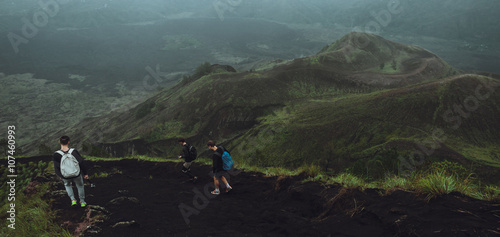 3 Men walk along the hill with backpacks and with white clouds a photo