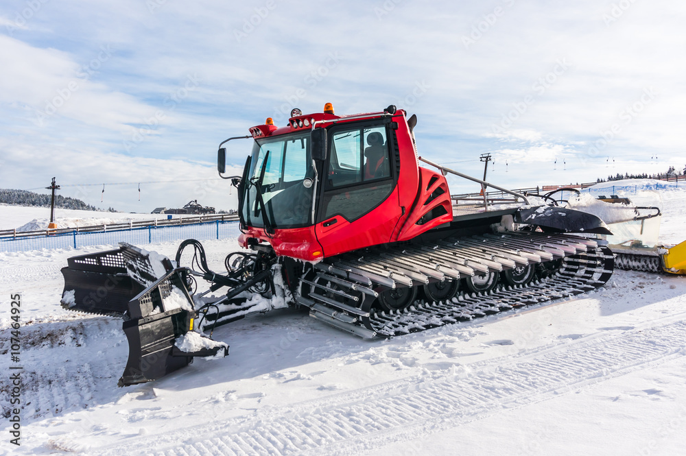 Red snow-grooming machine on snow Red snow-grooming machine on snow