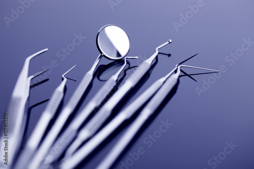 Dental mirror and other tools on blue shiny background