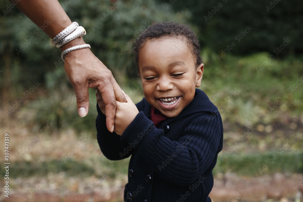 African American boy holding hand of mother in park African American boy holding hand of mother in park