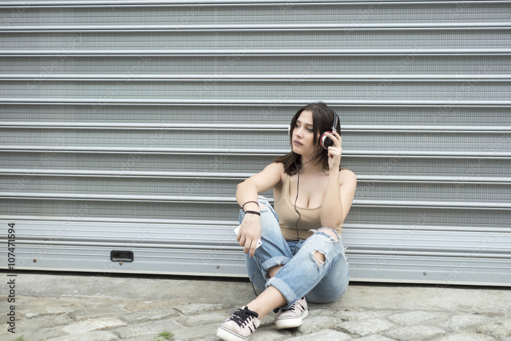 Obraz premium Young beautiful woman sitting down and listening music with head