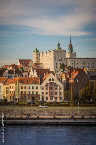 White castle with towers and green roofs and red roofs of residential and office houses and river in Szczecin, Poland