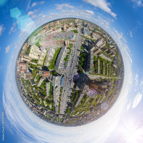 Aerial city view with crossroads and roads, houses, buildings, parks and parking lots, bridges. Copter shot. Little planet mode. Full sphere.