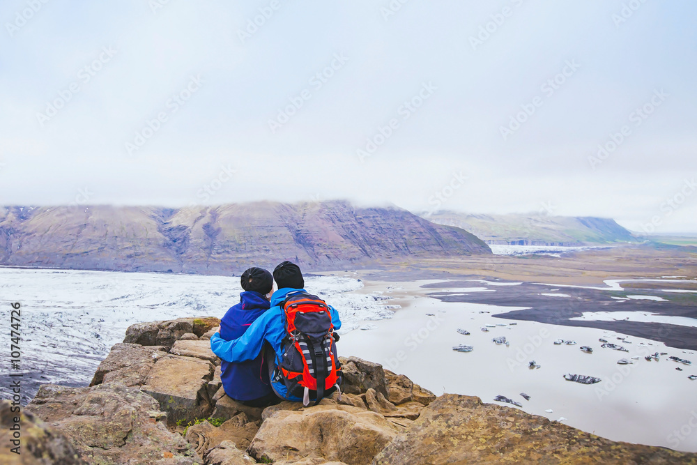 Φωτογραφία couple of hikers travel in Iceland, two backpackers enjoying view of glacier and
